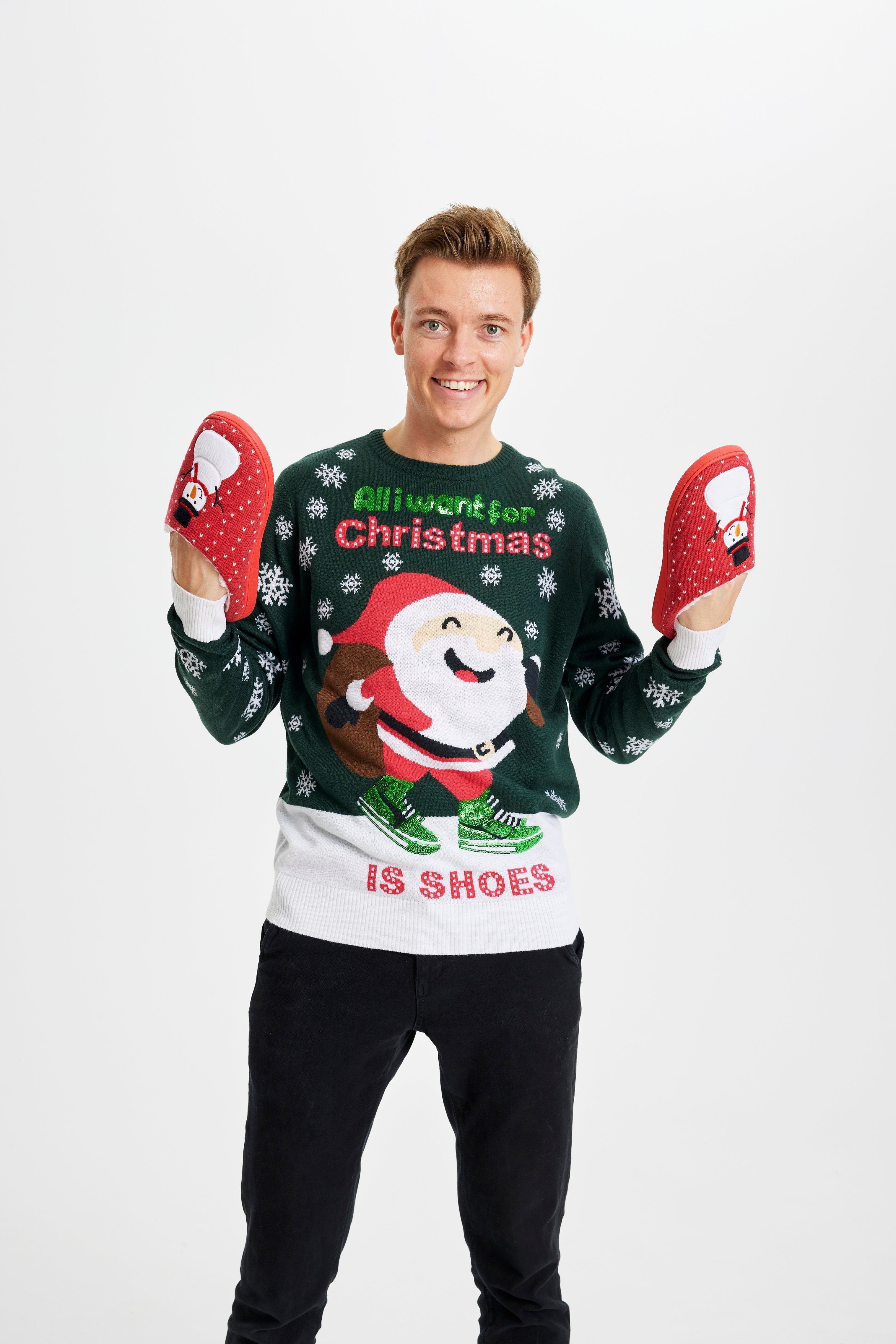 Un homme souriant portant un pull de Noël vert et blanc avec la citation
